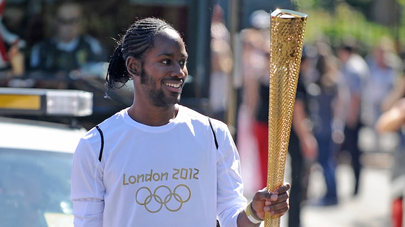 FILE -- Torchbearer Jason Arday carries the Olympic Flame on the Torch Relay leg between...